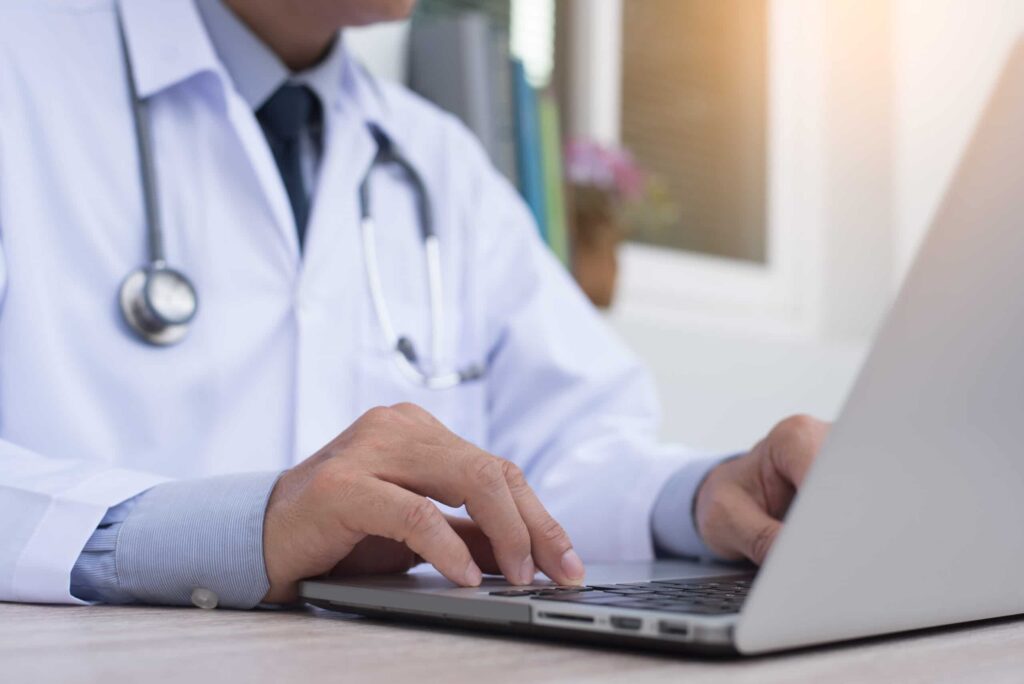 Close up image of a doctor working on a laptop on the table