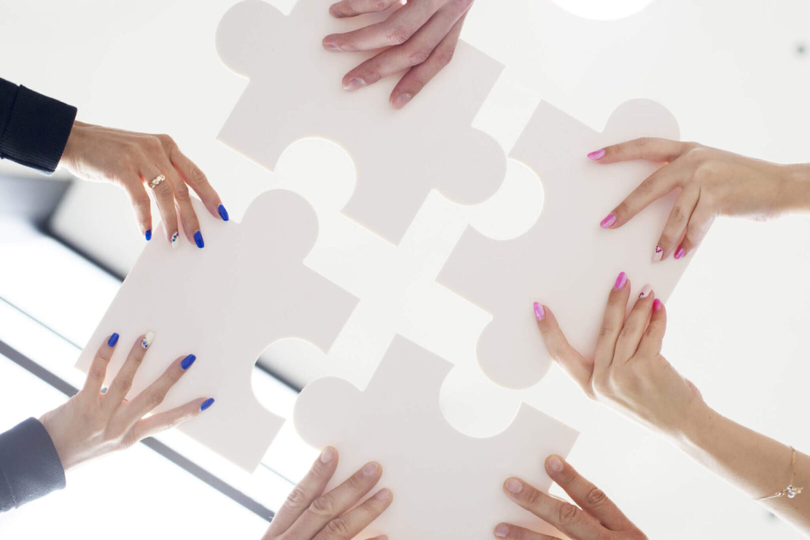 Hands of Business People Holding White Puzzle