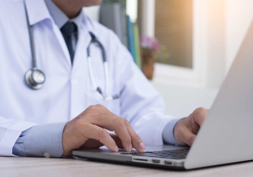 Close up image of a doctor working on a laptop on the table